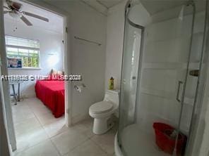 bathroom featuring ceiling fan, tile patterned floors, toilet, and walk in shower