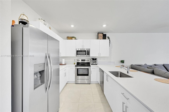 kitchen with kitchen peninsula, stainless steel appliances, sink, light tile patterned floors, and white cabinets