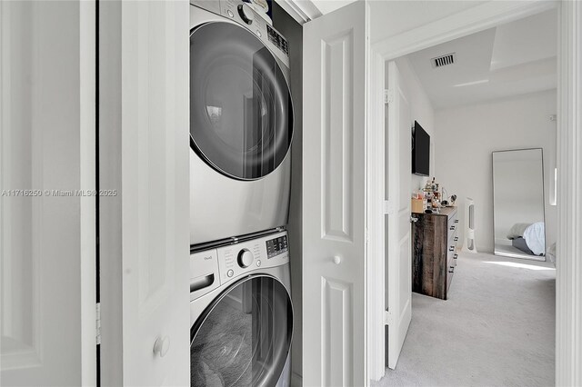 laundry room featuring light colored carpet and stacked washing maching and dryer