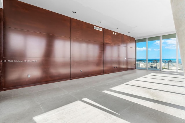 unfurnished room with floor to ceiling windows, a water view, and light tile patterned floors