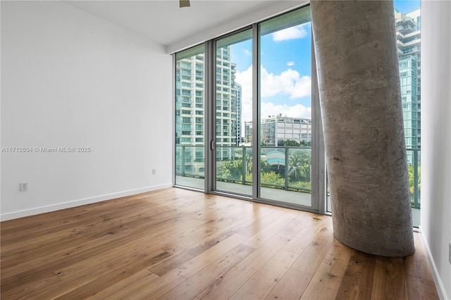 spare room with light hardwood / wood-style floors and a wall of windows