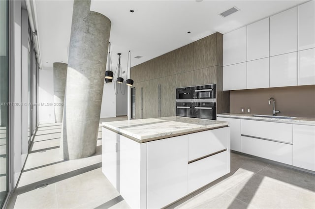 kitchen featuring a center island, sink, white cabinets, and black double oven