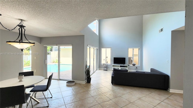 living room featuring a high ceiling, a textured ceiling, and light tile patterned floors