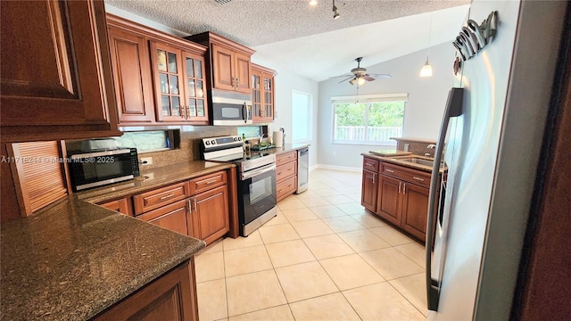 kitchen featuring lofted ceiling, ceiling fan, a textured ceiling, appliances with stainless steel finishes, and light tile patterned flooring