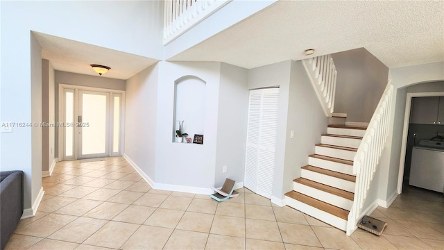 foyer featuring washer / clothes dryer, light tile patterned floors, and a textured ceiling