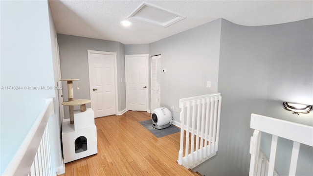 hallway with a textured ceiling and light hardwood / wood-style flooring