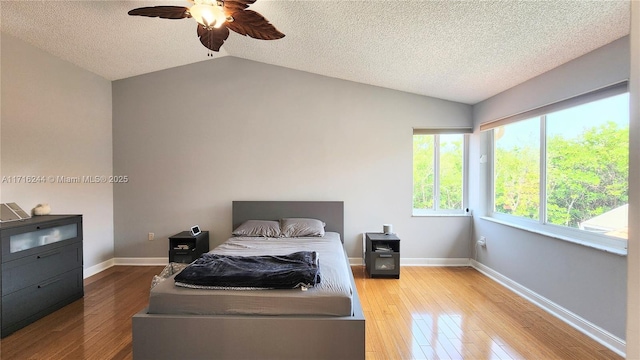 bedroom featuring ceiling fan, light wood-type flooring, a textured ceiling, and vaulted ceiling