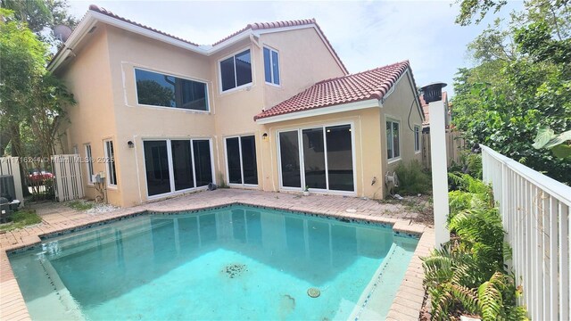 rear view of property featuring a fenced in pool