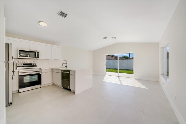 kitchen featuring lofted ceiling, a wealth of natural light, stainless steel appliances, and white cabinetry