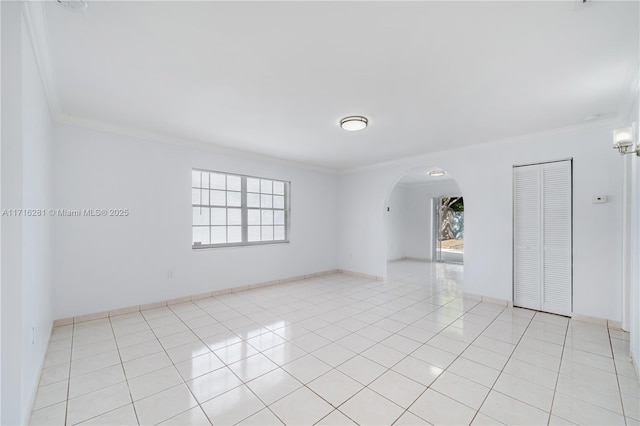 spare room with a healthy amount of sunlight, ornamental molding, and light tile patterned floors