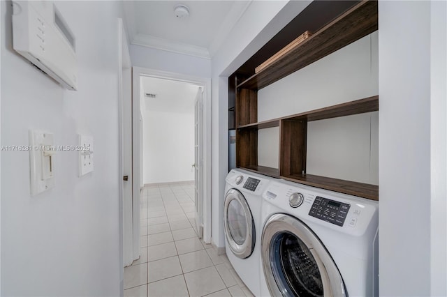 laundry room with washing machine and clothes dryer, crown molding, and light tile patterned floors