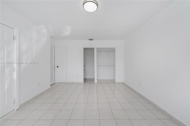 interior space with light tile patterned floors, ornamental molding, and a closet