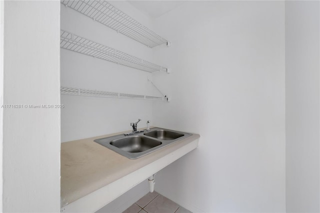 clothes washing area featuring light tile patterned floors and sink