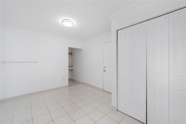 unfurnished bedroom featuring a closet, light tile patterned flooring, and ornamental molding