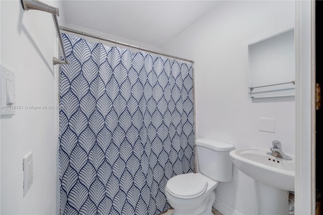 bathroom featuring a shower with curtain, toilet, and sink