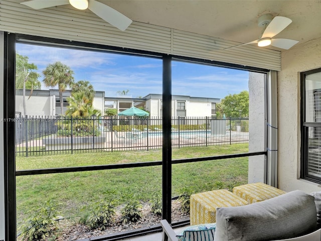 sunroom / solarium featuring a residential view and ceiling fan