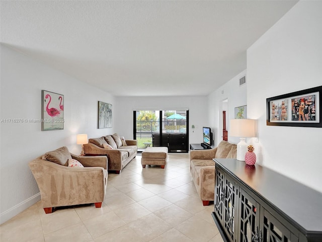 living area with light tile patterned floors, baseboards, visible vents, and a textured ceiling