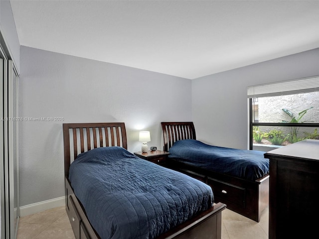bedroom featuring light tile patterned floors, baseboards, and a closet