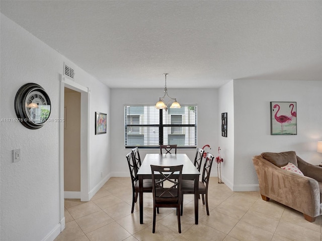 dining area featuring light tile patterned floors, visible vents, baseboards, and a textured ceiling