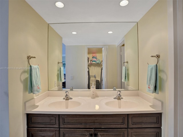 bathroom with a sink, double vanity, and recessed lighting