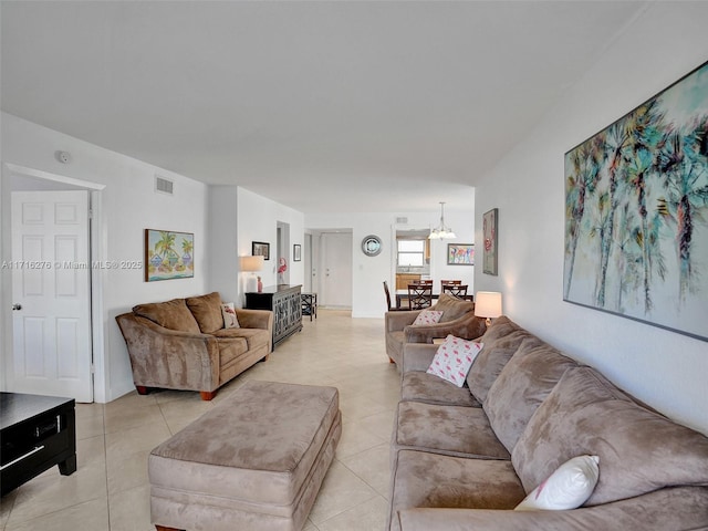 living room featuring light tile patterned flooring, visible vents, and a notable chandelier