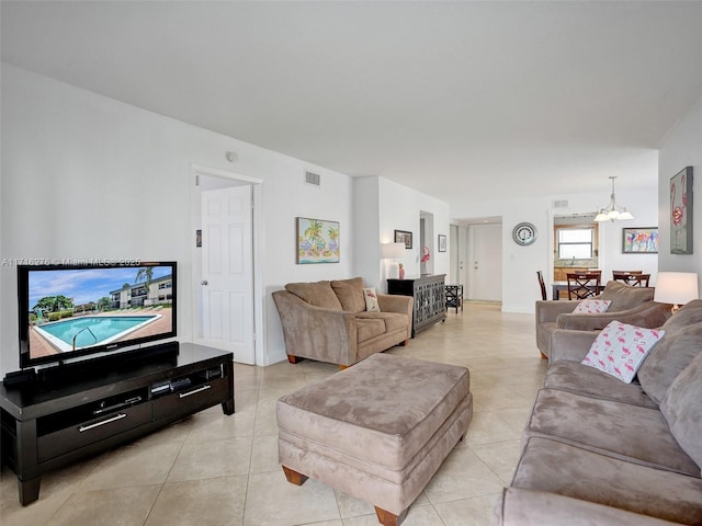 living room featuring light tile patterned floors, visible vents, and a notable chandelier