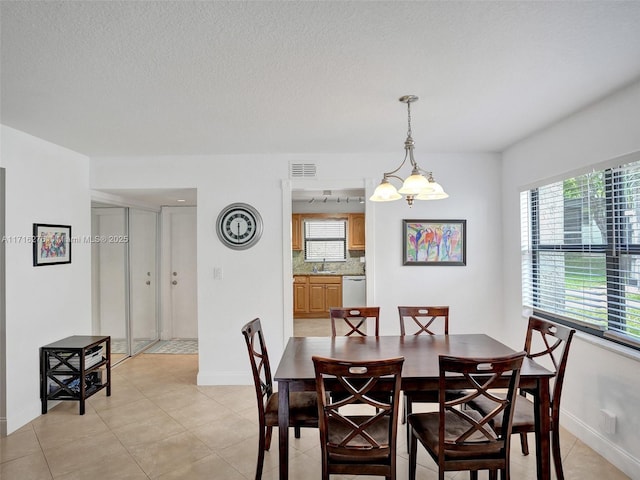dining space featuring a textured ceiling, baseboards, visible vents, light tile patterned flooring, and a chandelier