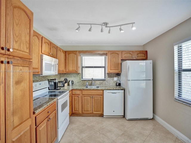 kitchen with a sink, white appliances, light stone counters, backsplash, and light tile patterned floors