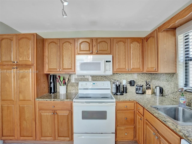 kitchen featuring a sink, white appliances, tasteful backsplash, and light stone counters