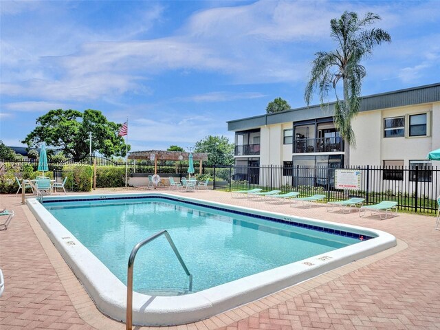 community pool with a pergola, a patio, and fence