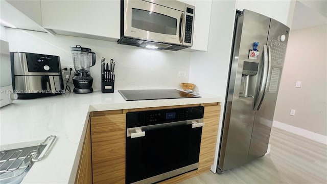 kitchen with light hardwood / wood-style floors, white cabinetry, and appliances with stainless steel finishes