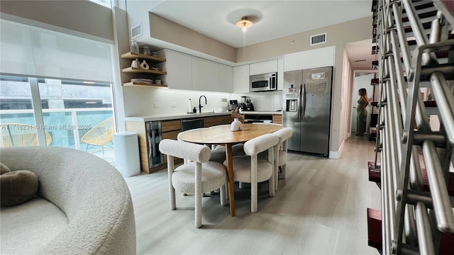 kitchen featuring sink, light wood-type flooring, white cabinetry, and stainless steel appliances