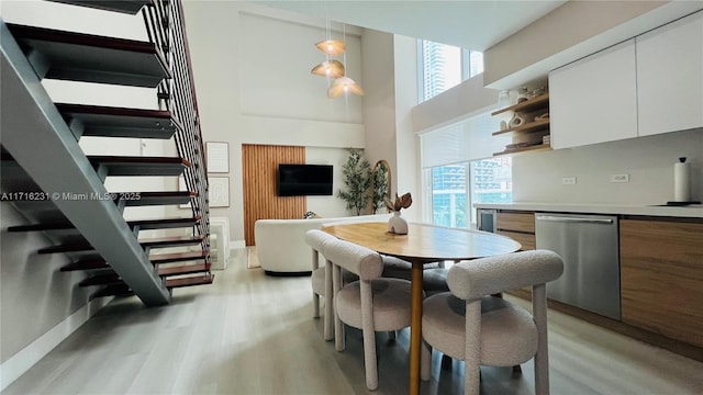 dining area with a towering ceiling and light hardwood / wood-style flooring