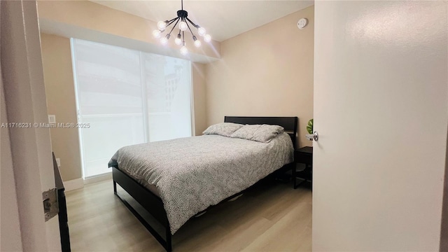 bedroom with a notable chandelier and light wood-type flooring