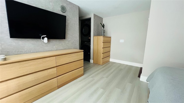 bedroom with light hardwood / wood-style flooring and stacked washer and clothes dryer