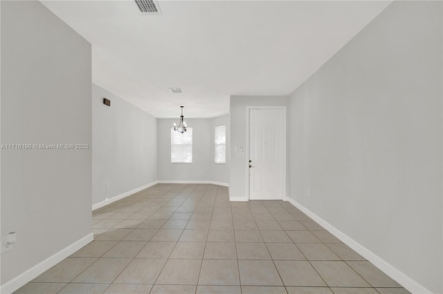 spare room with baseboards, visible vents, an inviting chandelier, and light tile patterned floors