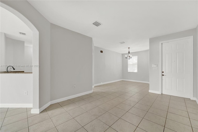 unfurnished room with light tile patterned floors, a chandelier, visible vents, and baseboards