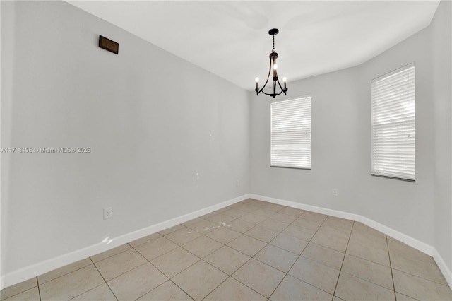 spare room with light tile patterned flooring, baseboards, and an inviting chandelier