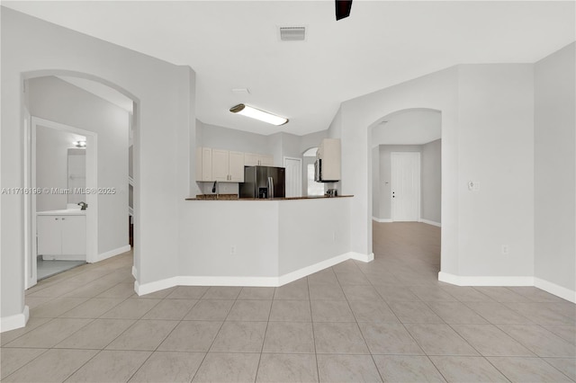 kitchen featuring light tile patterned floors, visible vents, arched walkways, and stainless steel fridge with ice dispenser