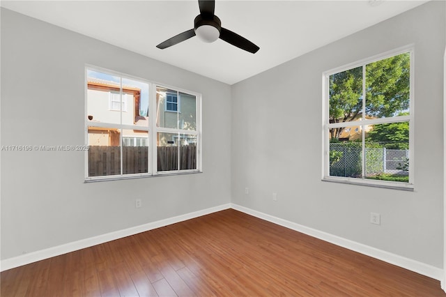 empty room with a ceiling fan, baseboards, and wood finished floors