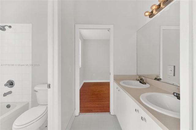 bathroom with double vanity, toilet, tub / shower combination, and a sink