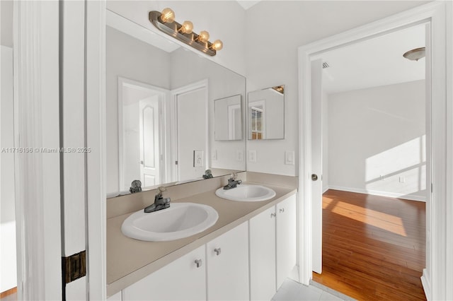 full bathroom with double vanity, wood finished floors, and a sink