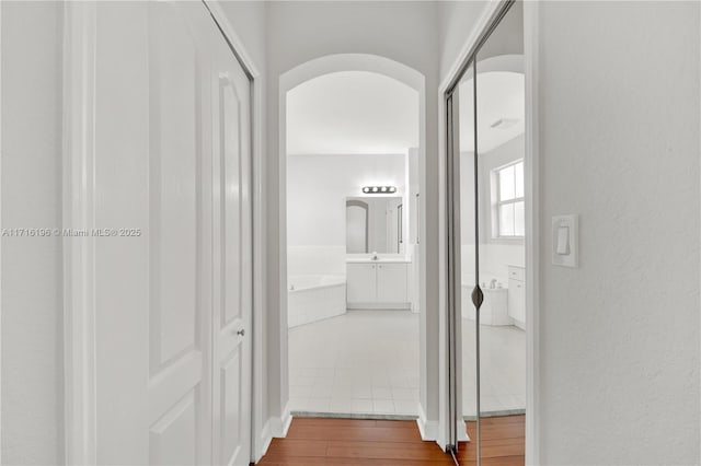 corridor featuring arched walkways and wood finished floors