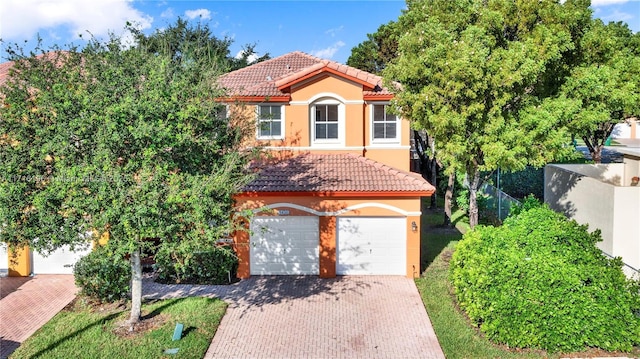 view of front facade featuring decorative driveway, fence, a tile roof, and stucco siding