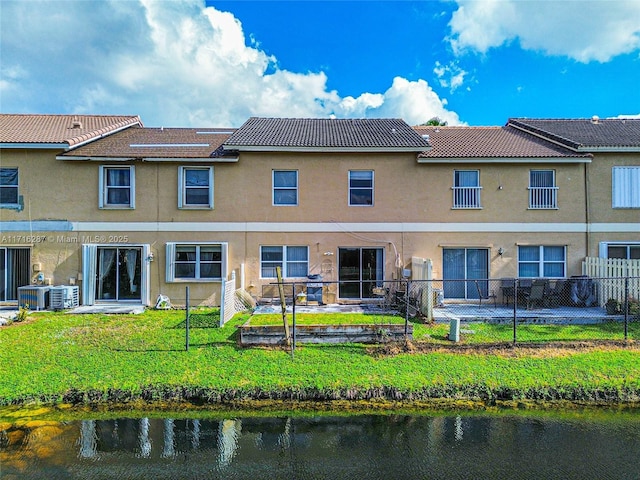 rear view of property featuring a lawn, a water view, and cooling unit