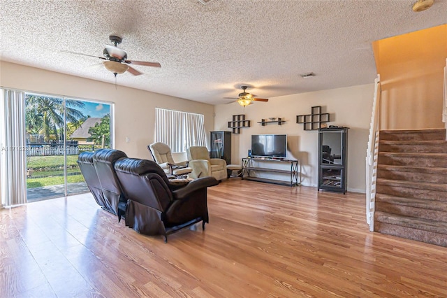 living room featuring hardwood / wood-style floors, ceiling fan, and a textured ceiling