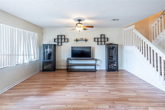 unfurnished living room with ceiling fan, a textured ceiling, and light hardwood / wood-style flooring