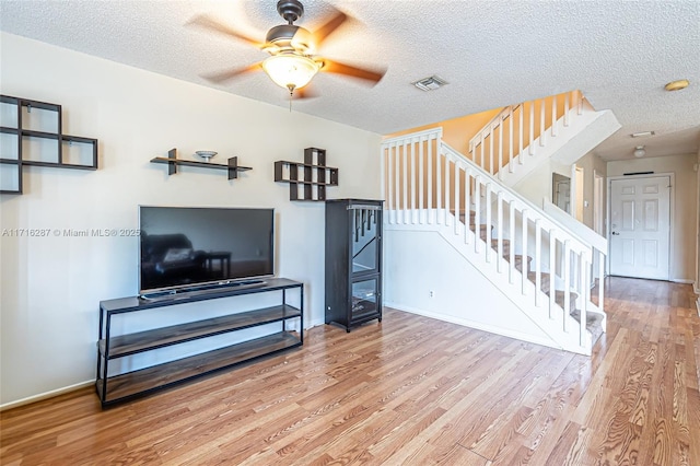 living room featuring hardwood / wood-style floors, ceiling fan, and a textured ceiling