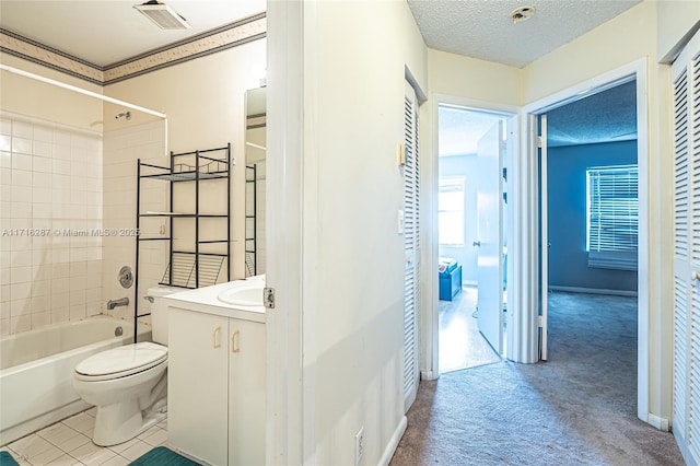 full bathroom with vanity, toilet, a textured ceiling, and tiled shower / bath combo