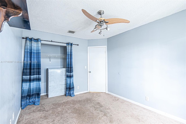 unfurnished bedroom with ceiling fan, carpet floors, and a textured ceiling